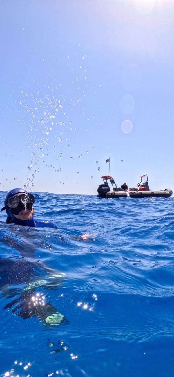 Dawid psitting water out with Fabrice in the back ground in the Freediving boat